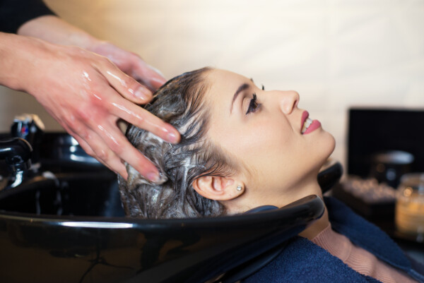 Hairdresser washing hair of the woman in modern hair salon