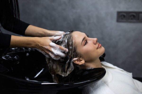 beauty and people Happy young woman with hairdresser washing head at hair salon