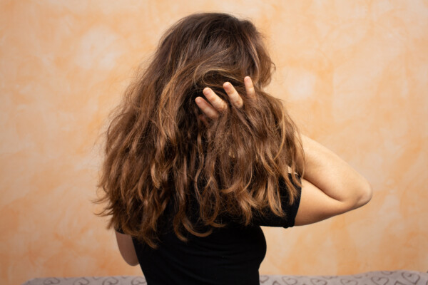 girl with long, dry hair tangles it with her hand